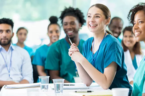 Fröhliche weibliche Pflegestudenten lächeln, während sie einer Vorlesung des Professors zuhören