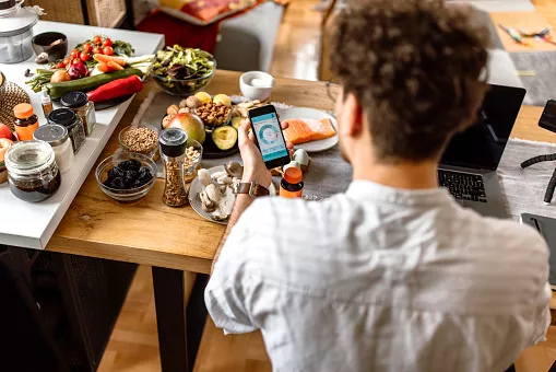 Student verfolgt Nahrungsaufnahme mit einer mobilen App zu Hause.