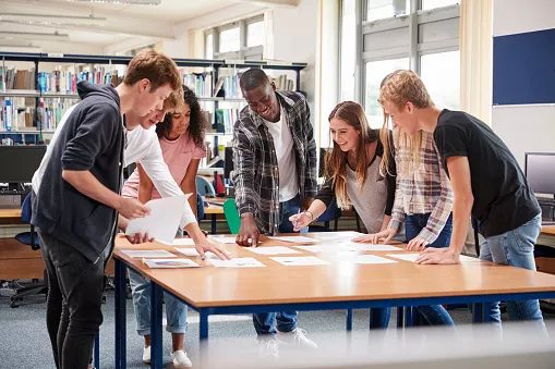 Gruppe von Student:innen arbeitet gemeinsam an einem Projekt in der Bibliothek.