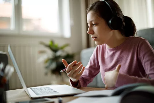 Studentin mit Kopfhörern hat Online-Vorlesung zu Hause.