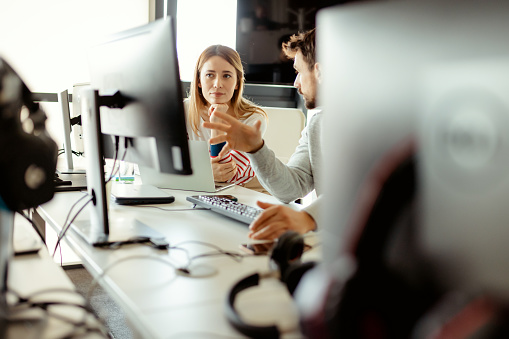 Zwei Personen sitzen vor einem Computer und reden