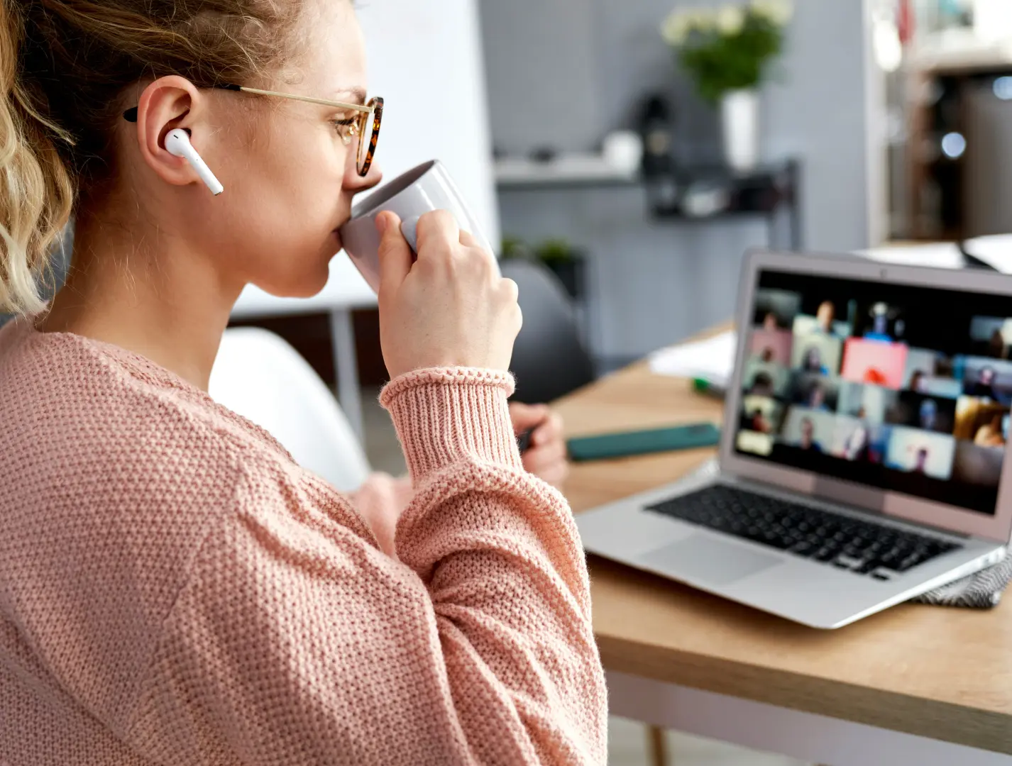 Frau sieht sich Webinar an und trinkt dabei Kaffee